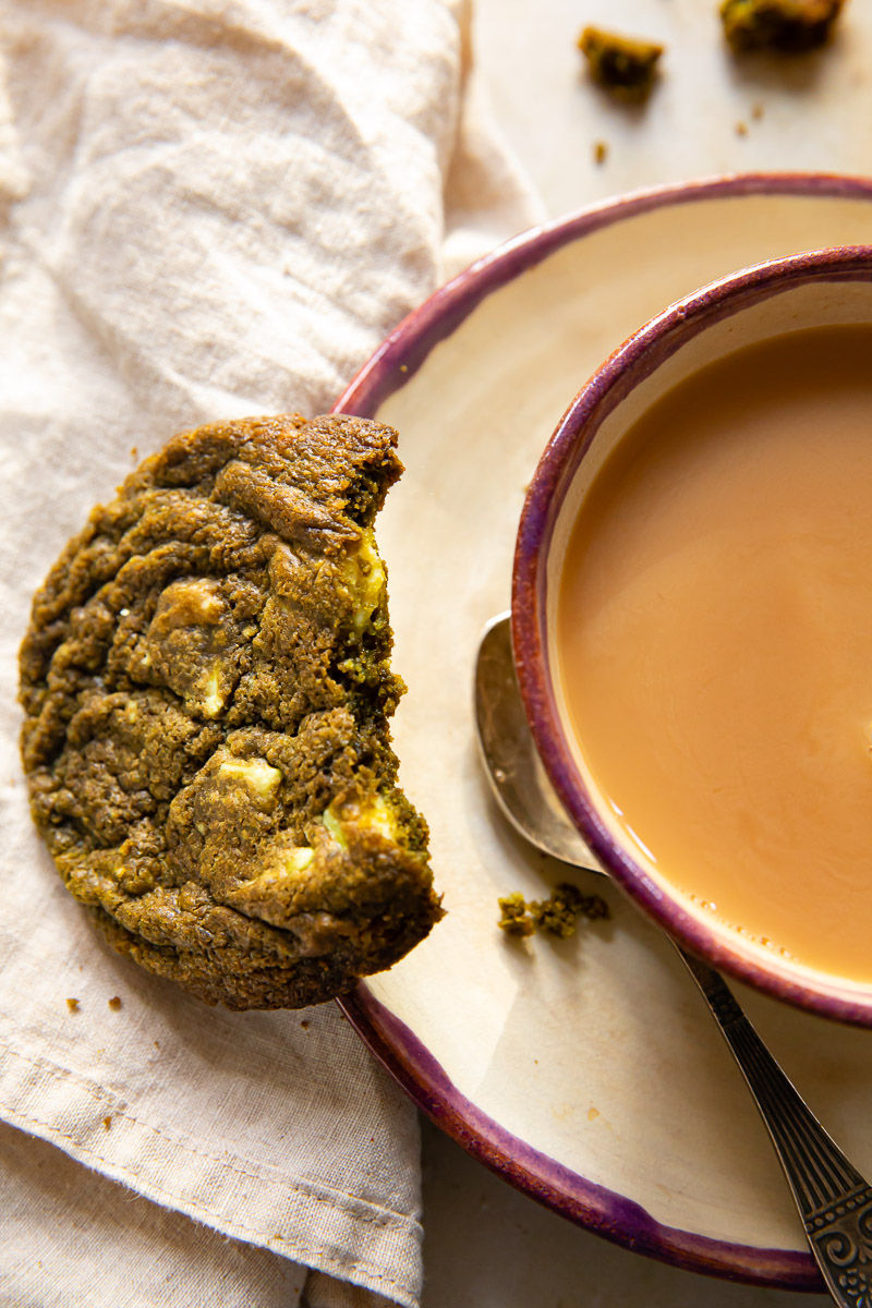 top down view of a cup of tea on a saucer and a half eaten cookie