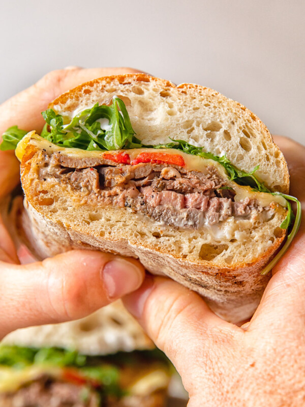 Hands holding hot roast beef sandwich
