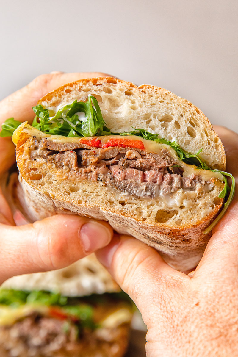 Hands holding hot roast beef sandwich