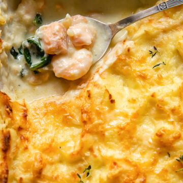 top dow view of fish pie with a spoon holding the creamy filling of fish pieces