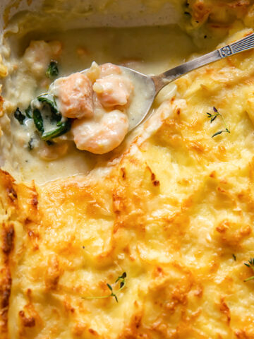 top dow view of fish pie with a spoon holding the creamy filling of fish pieces