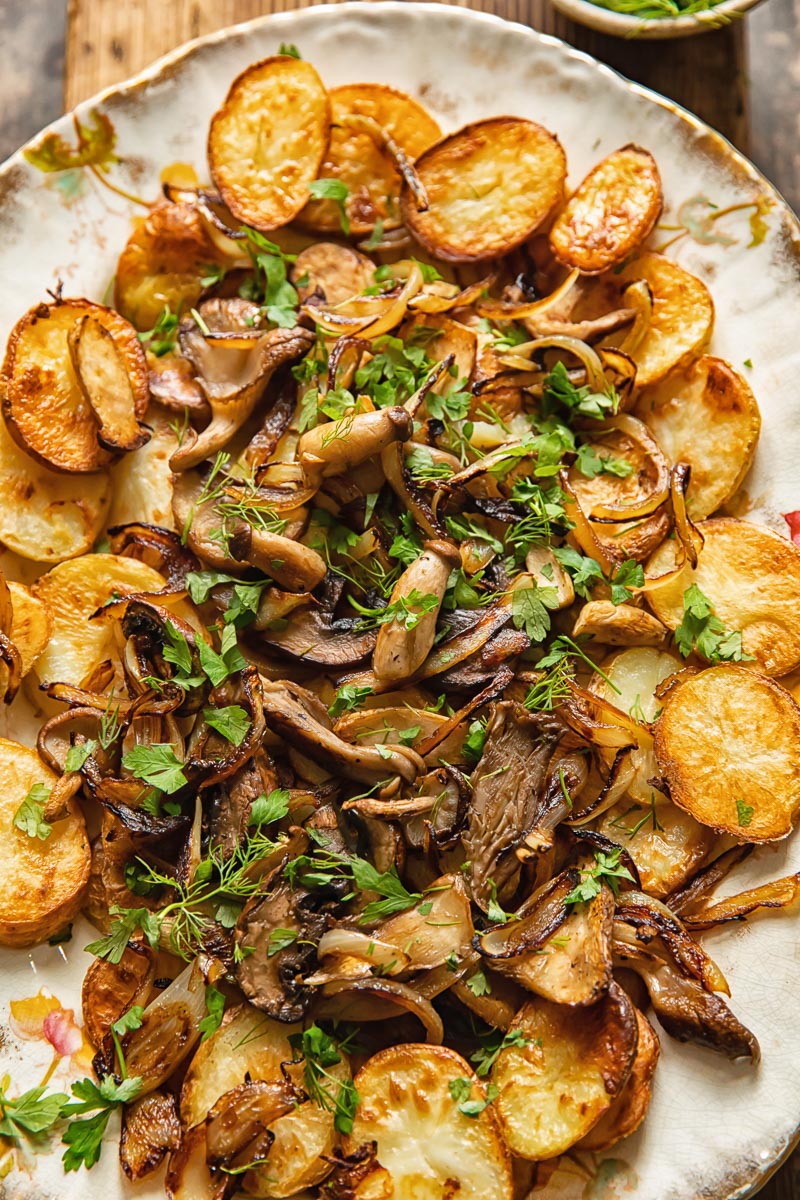 fried potato disks topped with fried mushrooms and onions on a serving platter