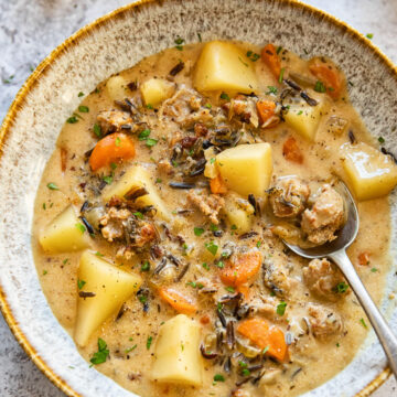 potato and sausage chowder in a soup bow with a spoon in it