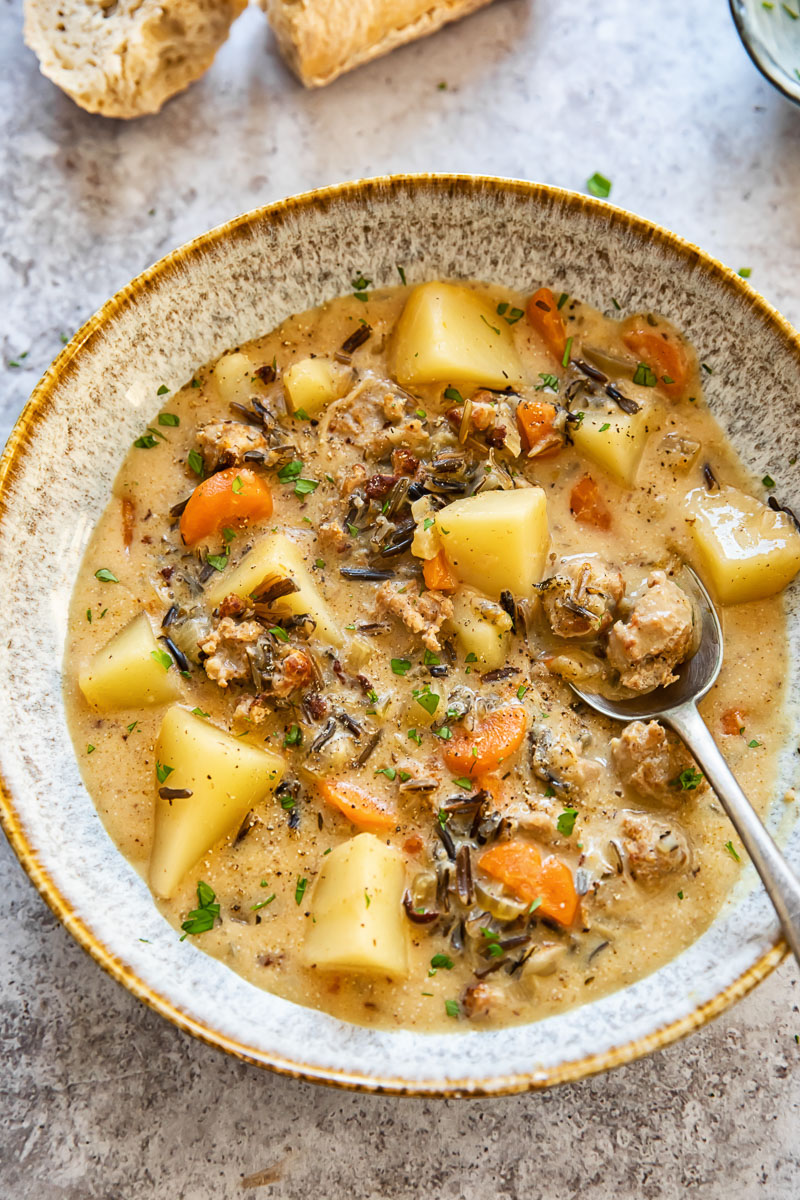 potato and sausage chowder in a soup bow with a spoon in it