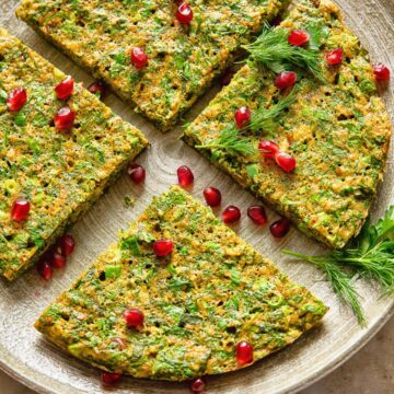top down view of herby frittata cut into 4 wedges and topped with pomegranate seeds