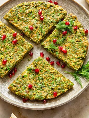 top down view of herby frittata cut into 4 wedges and topped with pomegranate seeds