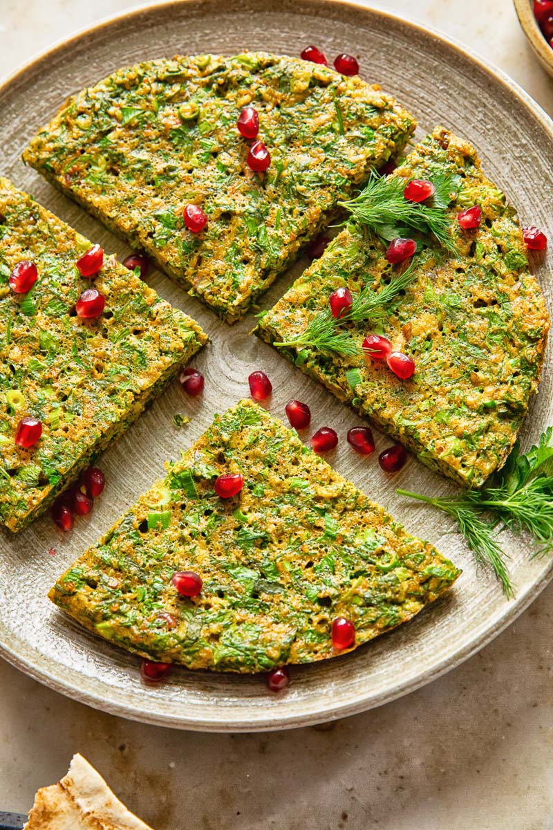 top down view of herby frittata cut into 4 wedges and topped with pomegranate seeds