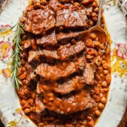 top down view of sliced pot roast with vegetables and chickpeas on a platter