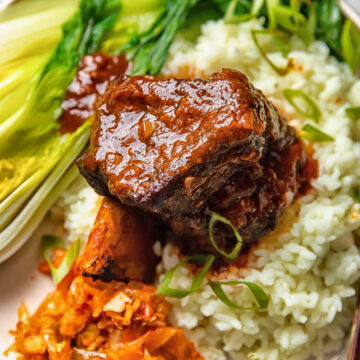 short rib on a bed of rice with bok choy and kimchi on a plate