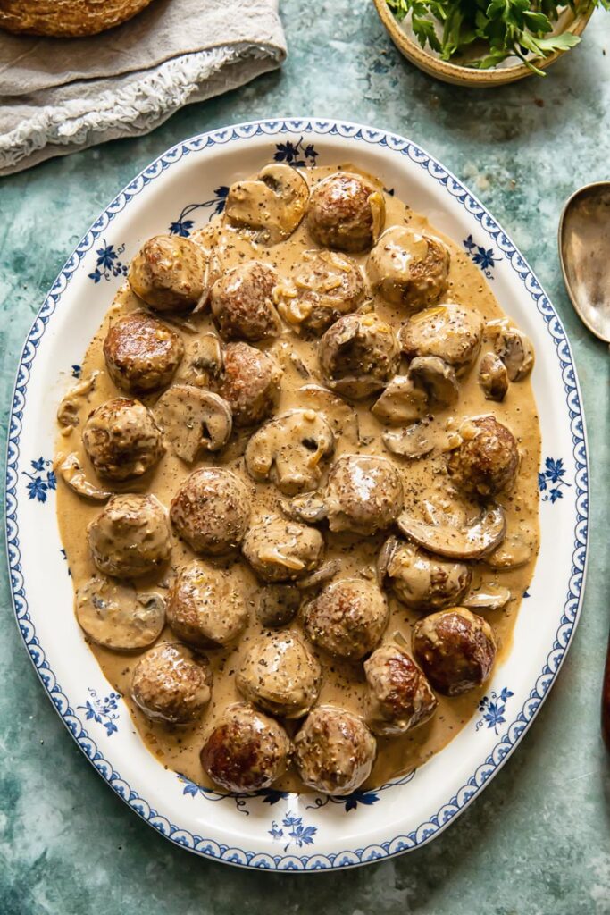 top down view of meatballs in a creamy sauce on a white and blue platter