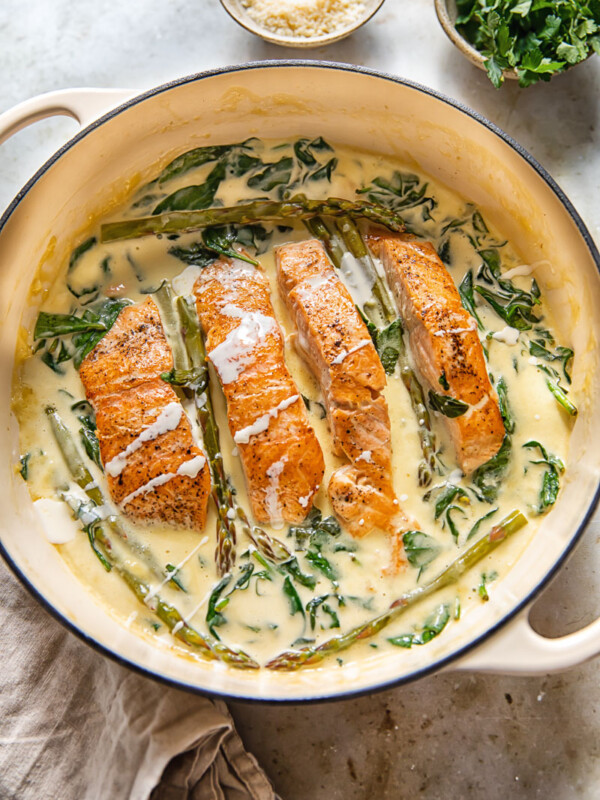 top down view of salmon filets in a creamy sauce with spinach and asparagus