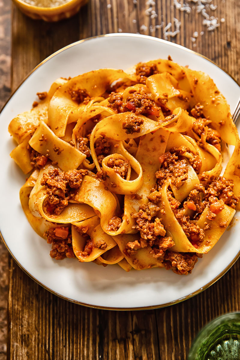 top down view of pappardelle with meaty tomato sauce on a white plate