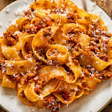 pasta with ragu sauce on a while place and a fork