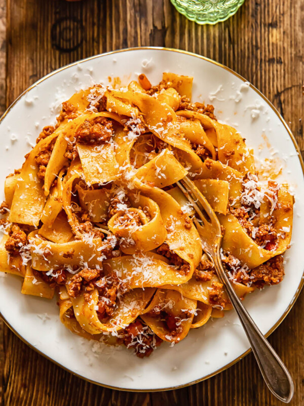 top down view of pappardelle pasta with sauce on a white plate.