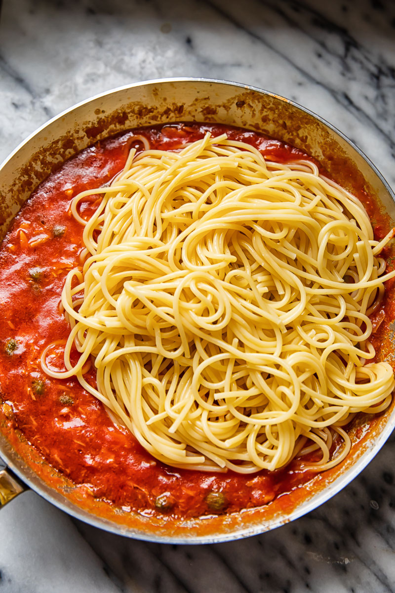 spaghetti on top of red sauce in a pan