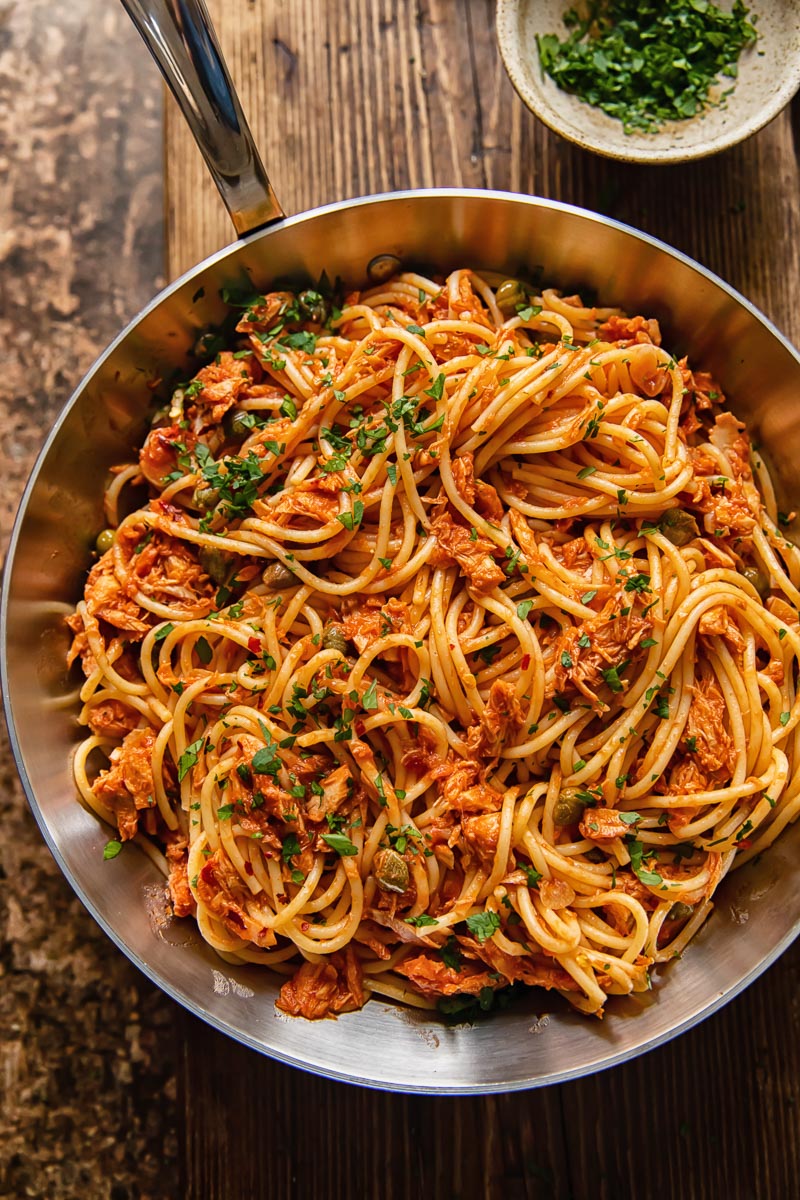 top dow view of tuna pasta in a tomato sauce in a pan on dark wood background