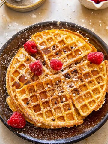 round Belgian waffles topped with raspberries, icing sugar and sprinkles