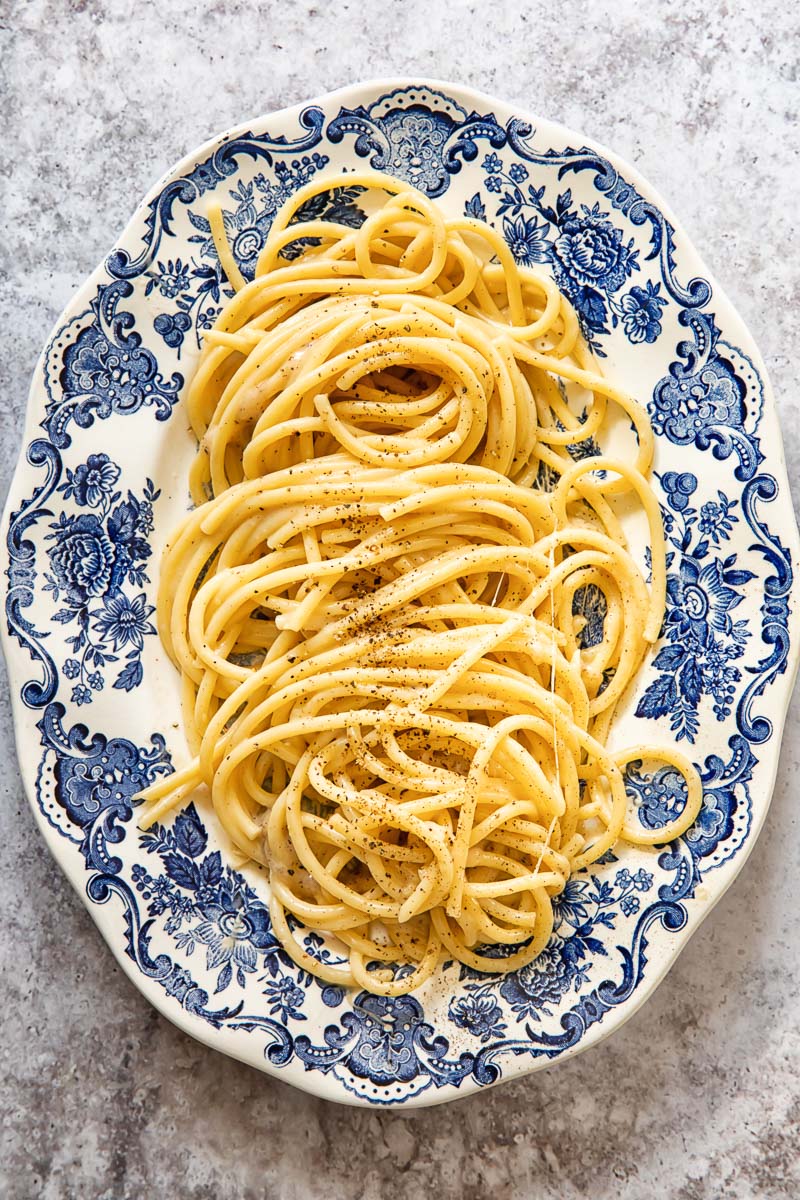 bucatini cacio e pepe on a blue and white oval platter