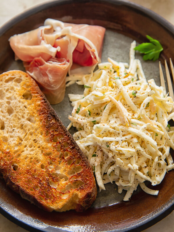 top down view of brown plate with celeriac remoulade, toasted bread slice and Parma ham slice