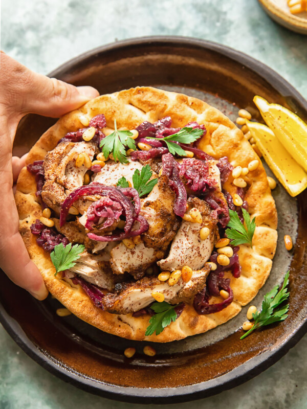Person grabbing Chicken Musakhan on flatbread