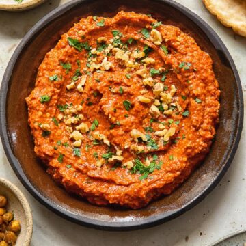 Top down view of Muhammara dip in bowl sprinkled with walnuts and parsley