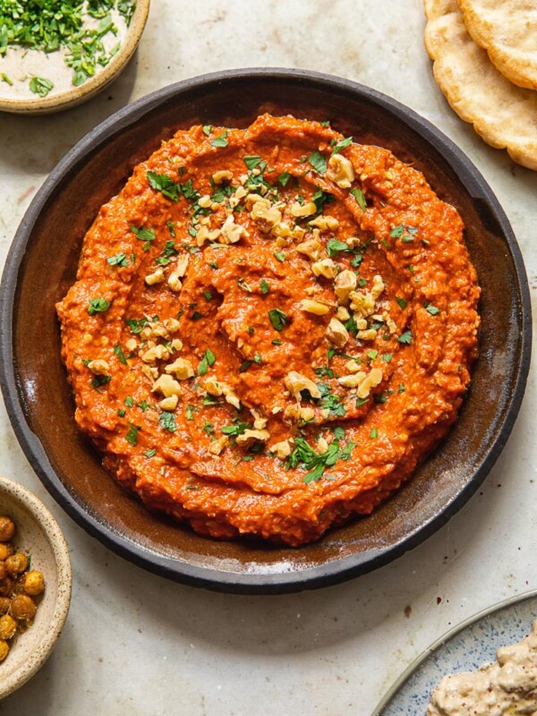 Top down view of Muhammara dip in bowl sprinkled with walnuts and parsley