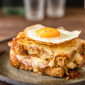Side view of croque madame sandwich with egg on top on a plate