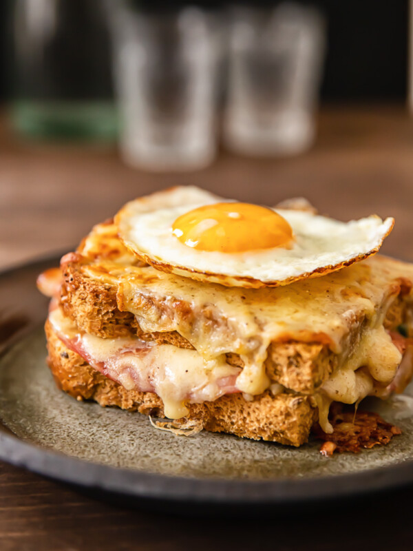 Side view of croque madame sandwich with egg on top on a plate