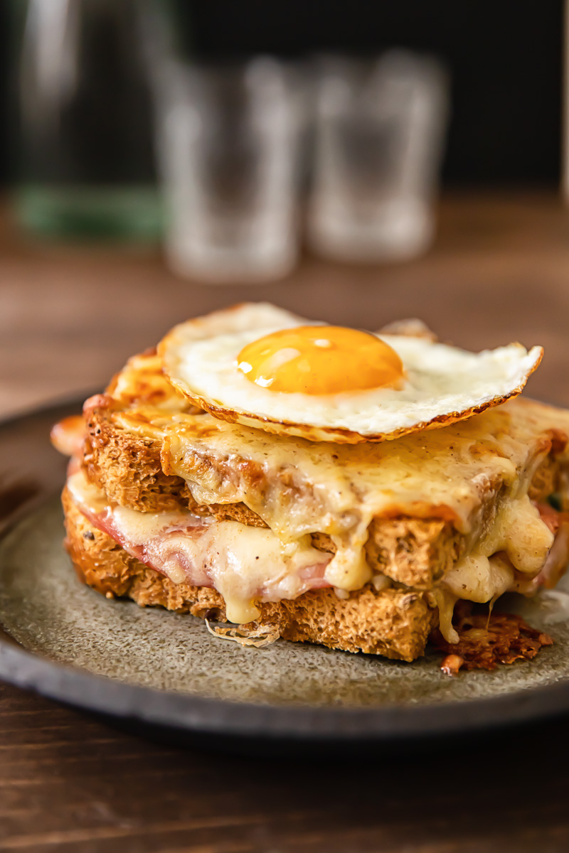 Side view of croque madame sandwich with egg on top on a plate