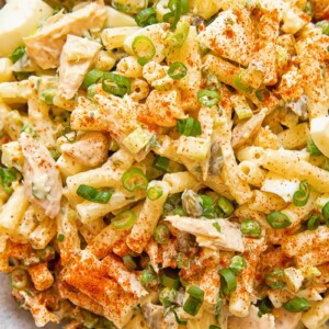 Close up of tuna macaroni salad with peas and green onion in a bowl.