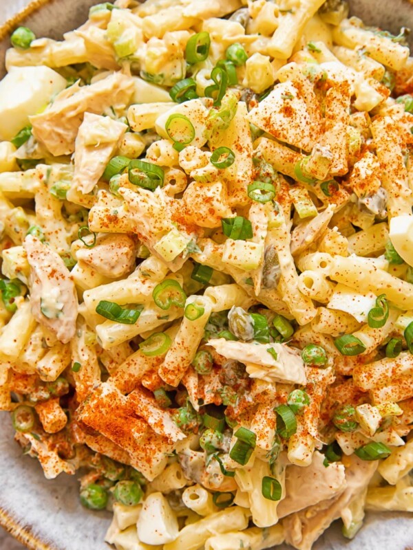 Close up of tuna macaroni salad with peas and green onion in a bowl.