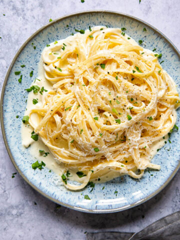 Close up if a plate of pasta cream sauce with sprinkled parsley