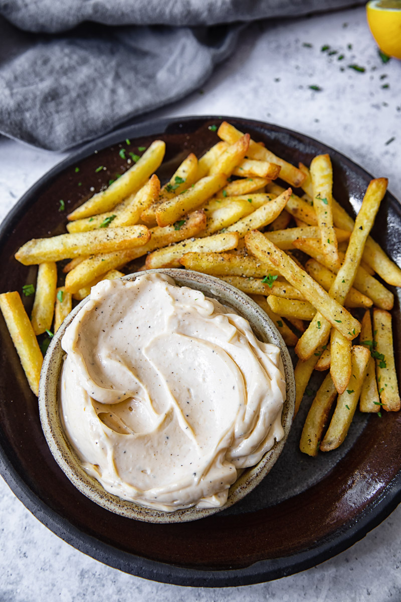 Top down view of truffle aioli surrounded by fries on a plate