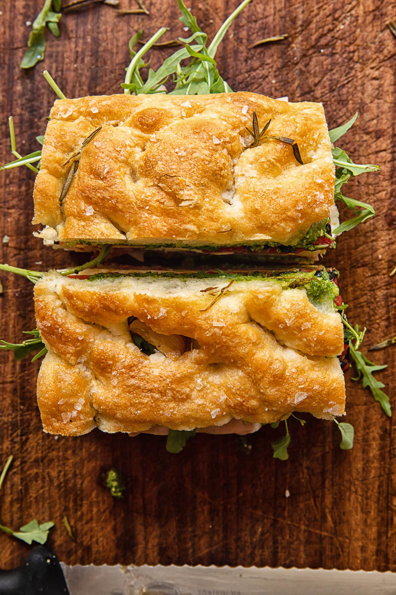 top down view of focaccia sandwich cut into halves on cutting board