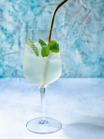 Side shot of a glass of mojito spritz with a straw