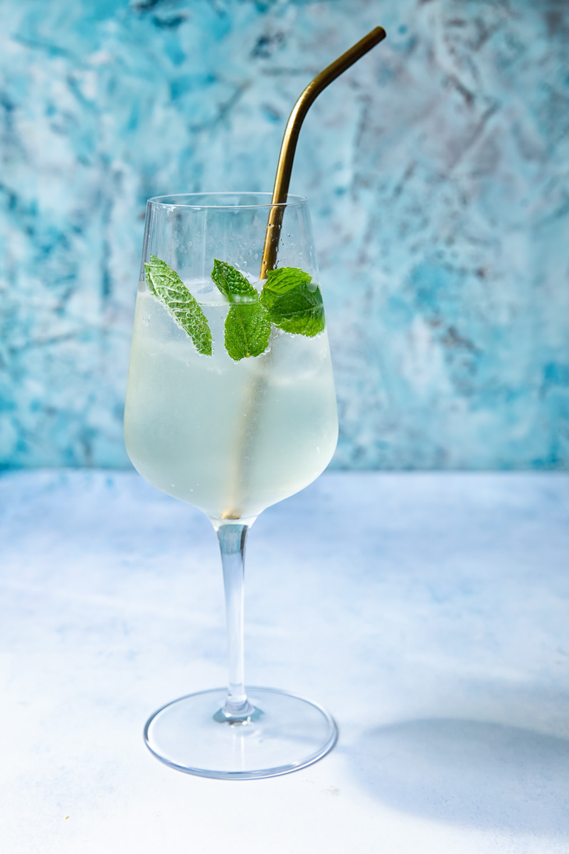 Side shot of a glass of mojito spritz with a straw