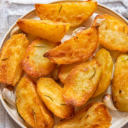 Top down view of golden roast potatoes on a plate.