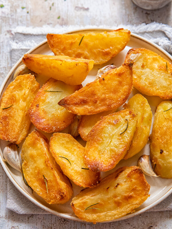 Top down view of golden roast potatoes on a plate.