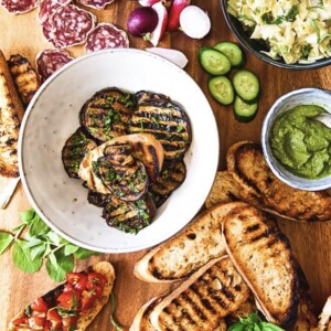 Spread of appetizers centered on grilled artichoke