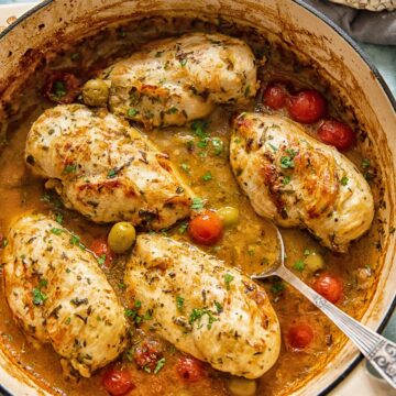 top down view of chicken breasts with olives, tomatoes in a pan sauce