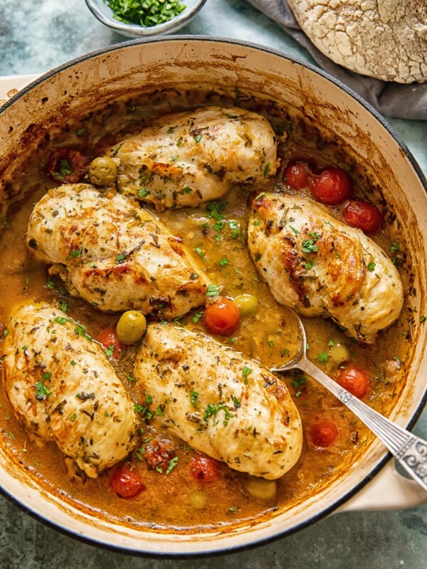 top down view of chicken breasts with olives, tomatoes in a pan sauce