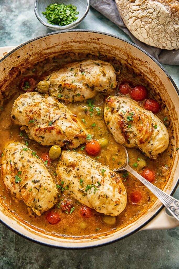 top down view of chicken breasts with olives, tomatoes in a pan sauce