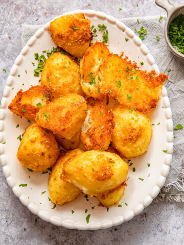 Top down view of parmesan crusted potatoes with chives on a platter