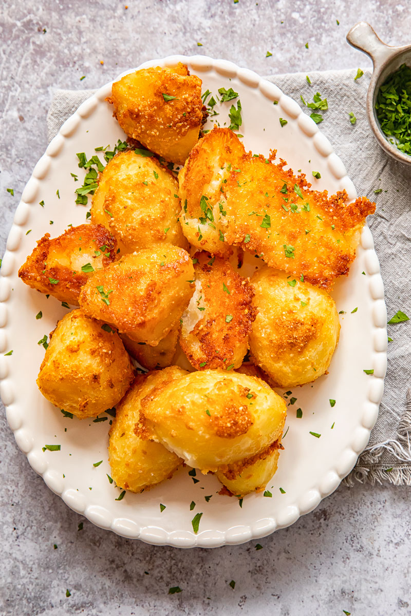 Top down view of parmesan crusted potatoes with chives on a platter