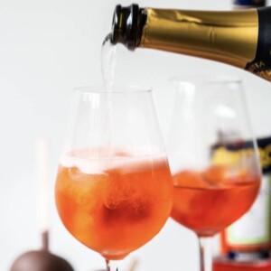 Close up of aperol spritz in wine glasses with prosecco pouring in