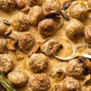 Top down view of spoon scooping meatballs in Marsala sauce from a pan