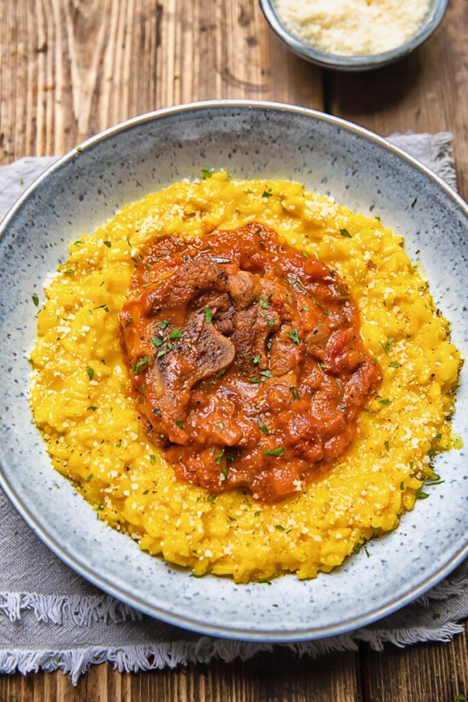 bowl of risotto with a red tomato and mushroom topping