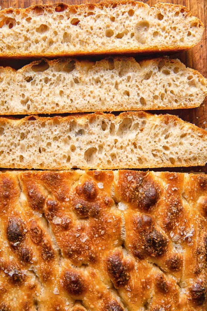 Close up shot of sourdough focaccia slices next to bread loaf