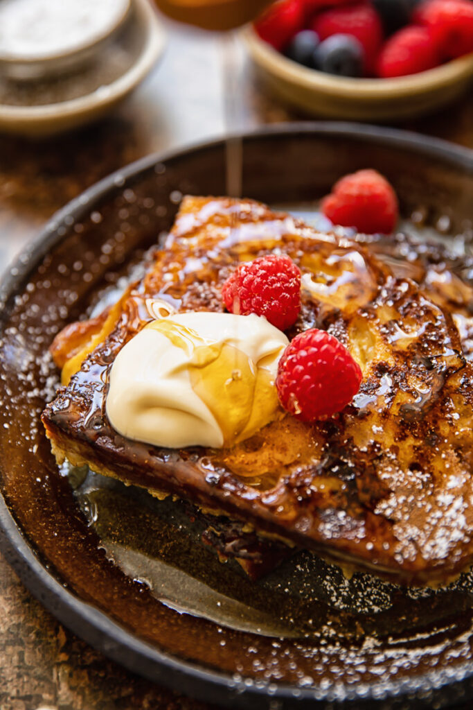 Close up shot of maple syrup being drizzled over creme fraiche on french toast