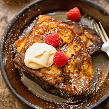 Top down shot of french toast with creme fraiche and raspberries on a plate